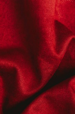 Zengin kırmızı kumaş yumuşak ışıkla nazikçe katlanır ve aydınlatılır. Yumuşak dokusunu ve canlı rengini gösterir..