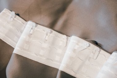 Genellikle giysi parçalarını güvence altına almak için terzilikte kullanılan beyaz klipsleri içeren kumaş perdelerin ayrıntılı bir görüntüsü.