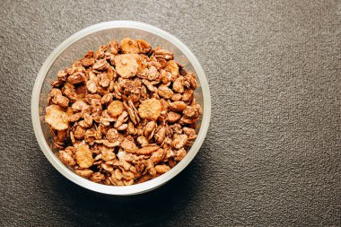 Sağlıklı kahvaltı ve atıştırmalıklar için mükemmel bir arka planda açık bir kasede gevrek ve tatlı bir granola karışımı sergilenir..