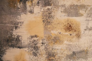 Düz olmayan bir duvar yüzeyi, soyulmuş boya katmanlarını, çarpıcı bir soyut görünüm yaratan doku ve renkleri gösterir..