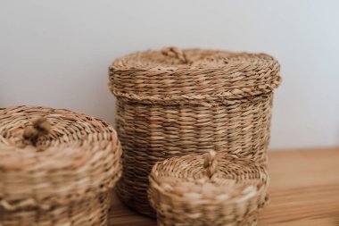 Değişen boyutlarda üç doğal dokuma sepetinin ahşap bir yüzeye yerleştirilmesi minimalist ve rahat bir atmosferi güçlendirir..