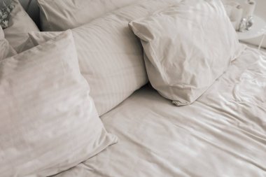 Pürüzsüz beyaz yastıklar ve yumuşak yatak odaları rahat bir ortam yaratıyor. Sıcak tonlar gevşemeyi artırır.