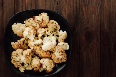 Taze karnabahar çiçekleri siyah bir kasede düzgünce düzenlenmiş altın kahverengiye kızartılır. Sağlıklı bir yemek için mükemmel..