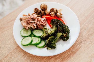 Besleyici yemek vitrinleri salatalık dilimli ızgara tavuk brokolili kırmızı biber ve tabakta sotelenmiş mantar..