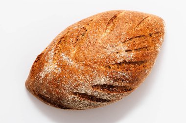 Kırsal kabuklu bir somun tam tahıllı ekmek, temiz bir yüzeye oturmuş, sanatsal dokusunu ve şeklini sergiliyor. Tazelik ve sıcaklık saçar..