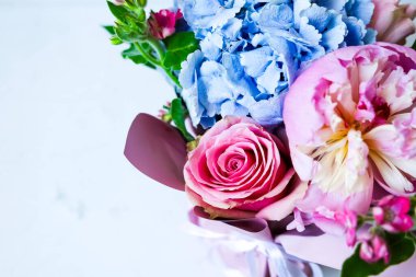 Yeşillik arasında pembe güller ve mavi ortancalardan oluşan bir buket zarafeti ön plana çıkarıyor. Kutlama için ideal..