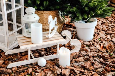 Büyüleyici bir gösteride, yeşil ve kırsal unsurlarla çevrili beyaz mumları olan ahşap bir kızak kış dekorasyonu için mükemmel..