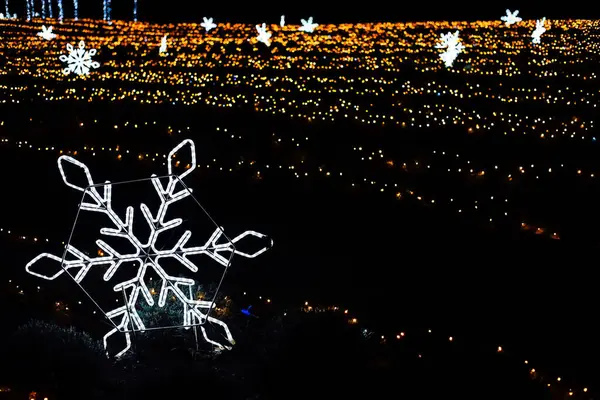 Canlı bir ışık gösterisi kar tanesi süslemeleri sergiliyor. Gece yapılan kış kutlamaları sırasında parıldayan binlerce ışığın arasında..