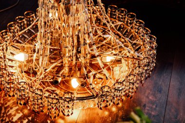 Karmaşık kristal süslemeleri olan güzel bir avize tavandan sarkıyor. Sıcak bir iç mekâna ışık saçıyor..