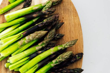 Canlı yeşil kuşkonmaz mızrakları, taze ve kaliteli olduklarını gösteren ahşap bir tahtanın üzerinde düzgünce düzenlenmiştir. Yemek ya da salata için mükemmel..