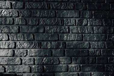 Koyu tuğlalı bir duvar, çeşitli ayarlar için karamsar bir zemin sağlayan ince ışık yansımalarına sahip desenli yüzeylere sahiptir..