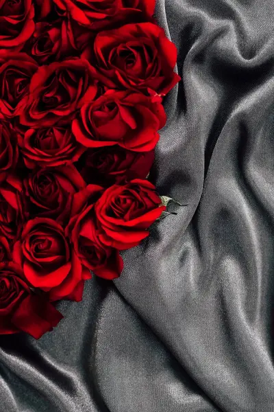 Canlı kırmızı güller yumuşak gri ipek üzerinde güzelce düzenlenir. Her romantik olay için mükemmel bir kontrast yaratır..