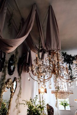 Güzel dekore edilmiş bir oda süslü avizeler kumaş örtüsü ve taze yeşillik ile büyüleyici bir atmosfer yaratıyor..