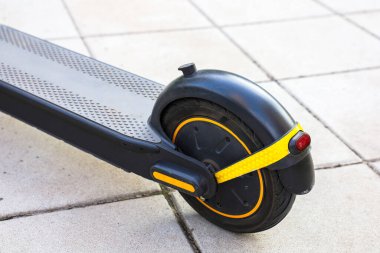 Gösterişli bir elektrikli scooter, tekerlek tasarımını ve canlı detaylarını sergileyen pürüzsüz gri bir kaldırıma dayanır..