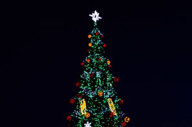 Neşeli bir Noel ağacı, renkli ışıklar ve süslerle parıldar ve neşeli bir tatil havası yaratır..