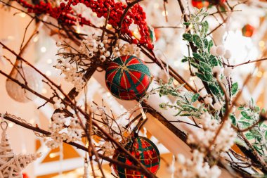 Süslemeler ve yeşillik güzel düzenlenmiş bir ağacı süslüyor ve tatil kutlamaları için sıcak ve davetkar bir ortam yaratıyor..