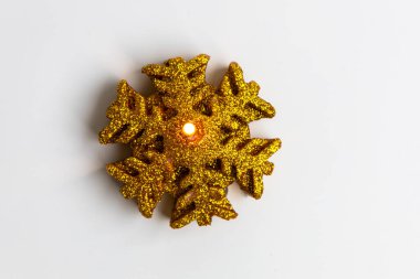 Altın parıldayan kar tanesi mumu beyaz bir yüzeyde oturur. Kış şenlikleri ve tatil toplantıları için sıcak bir ışıltı yaratır..