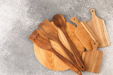 Çeşitli ahşap mutfak aletleri gri bir tezgahta sergileniyor. Farklı şekilleri ve dokuları yemek pişirmek için mükemmel..