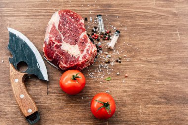 Çiğ pirzola iki olgun domates renkli biber ve yemek hazırlamak için ahşap tezgahta hazırlanmış keskin bir bıçak..