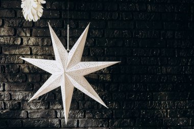 Sivri uçlu beyaz bir yıldız tavandan sarkıyor. Koyu renkli tuğla duvara karşı güzel bir kontrast oluşturuyor..