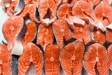 Çok sayıda somon filetosu bir market tezgahında düzgün bir şekilde sıralanır. Parlak turuncu et taze ve kalitesini gösteriyor. Yemek pişirmek ve suşi hazırlamak için mükemmel..