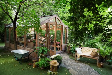 Canlı bitki ve ağaçların arasına yerleştirilmiş büyüleyici bir serada çeşitli çiçekler sergileniyor. Yakınlardaki ahşap bir bank bu huzurlu bahçeye rahatlamaya davet ediyor. Doğanın tadını çıkarmak için mükemmel..