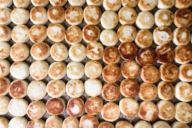 Altın şuruplu peynirli kekler düzgün bir sıra halinde tepsiye konur. Sıcak yumuşak doku ve taze pişmiş aroma havayı doldurur. Bu ekmekler sandviç ya da yemek için mükemmel..