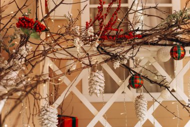 Canlı tatil süslemeleri kozalak kırmızı böğürtlen ve doğal bir ağaçtan sarkan süs eşyalarıyla sergilenir. Sıcak renkler hoş bir şenlik ortamı yaratır..