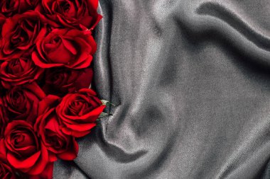 Fresh red roses are arranged neatly on a smooth gray fabric creating a stunning contrast that enhances the beauty of the flowers. This setup is perfect for romantic moments or celebrations.