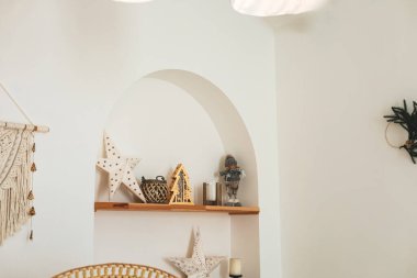 İyi tasarlanmış bir oda dekoratif raflar çeşitli süslemelerle süslenmiş. Açık renkli duvarlar sakin bir atmosfer yaratırken, eşsiz parçalar rahat ortama karakter katıyor..