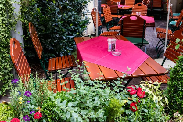 在露天餐厅的户外座位上 在被鲜花包围的露台上的木桌上放着五颜六色的红色桌布 — 图库照片
