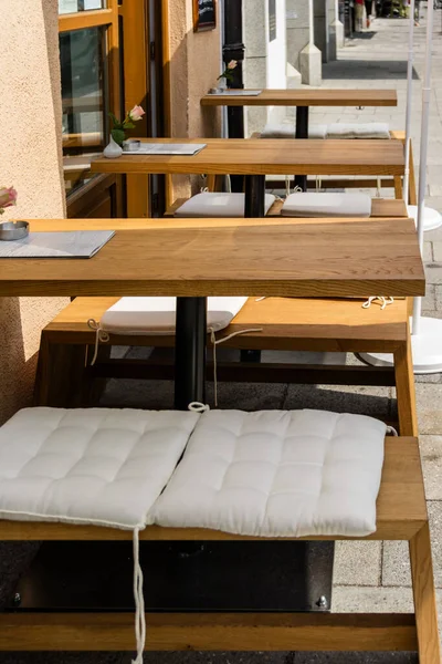 一排排小型的空户外抛光木长椅 为酒店或餐馆提供柔软的白色坐垫 — 图库照片