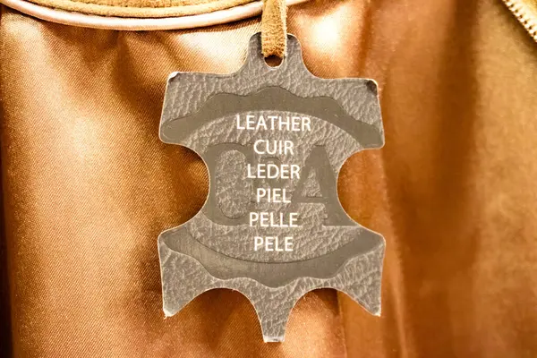 Leather label for genuine leather products in the international shield shape with white text displayed on merchandise in a store