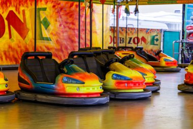 Bright colorful bumper cars at a fairground parked ready for renting on a covered rink clipart