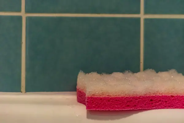 Close Foamy Pink Sponge White Bathtub Rim Next Glossy Green — Stock Photo, Image