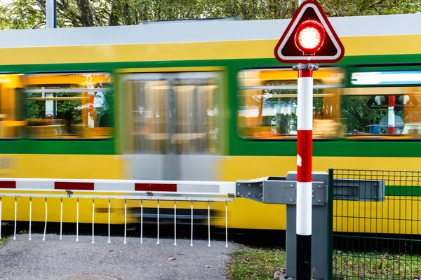 Gelber Personenzug Rast Durch Einen Bahnübergang Mit Heruntergelassenen Signalmasten Und — Stockfoto