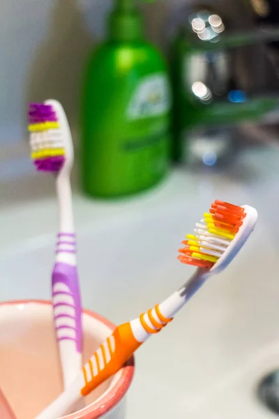 Две Разноцветные Оранжевые Фиолетовые Пластиковые Зубные Щетки Кружке Столешнице Ванной — стоковое фото