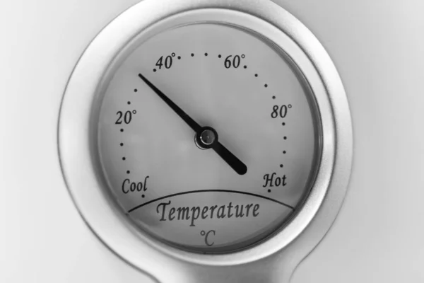 Dial or gauge on a thermostat from cool to hot to control the temperature on a white appliance in degrees Celsius