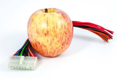 Beyaz arkaplanı olan bir bilgisayar kablosunun yanında olgun bir elmanın yakın plan fotoğrafı..