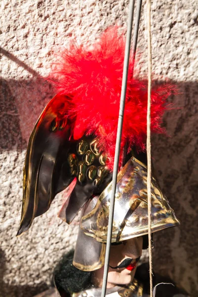 在有阴影的石墙前带剑的骑士上展示红色羽毛金属头盔 — 图库照片