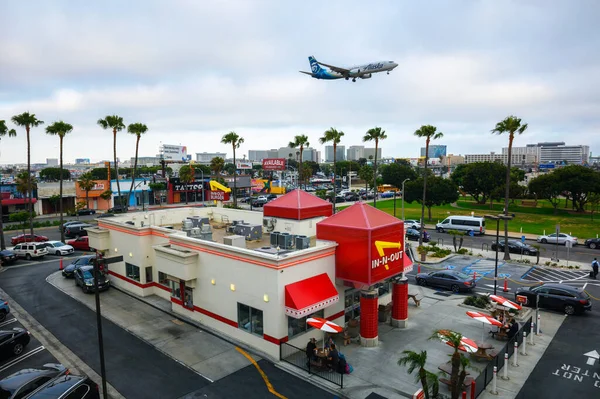 stock image Los Angeles, California, USA - May 26, 2022 : Alaska Airlines aircraft flying above a vintage In-N-Out Burger restaurant while landing at the Los Angeles International Airport LAX.