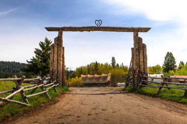 Moran, Wyoming, ABD - 8 Haziran 2022: Yılan Nehri 'ndeki Buffalo Vadisi Çiftliği girişinde arka planda tarihi vagonlar bulunuyor. Bu çiftlik Grand Teton Ulusal Parkı 'nda bulunmaktadır..