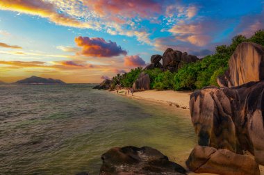 Seyşeller 'deki La Digue Adası' ndaki Anse Source Dargent plajında gün batımı renkli bulutlar, palmiye ağaçları ve muhteşem granit kaya oluşumlarıyla.