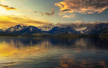 Tahoe Gölü 'nün yukarısında yaz günbatımı karlı Sierra Nevada Dağları ve suda güzel bir yansıma..