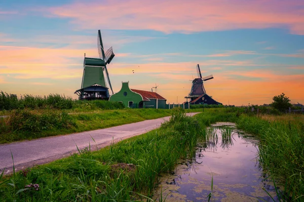 歴史的な農家住宅とオランダのアムステルダム近郊のザーンセスカンスの美しいオランダ村の風車の上夕日 — ストック写真