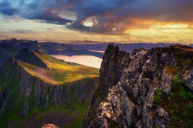 Norveç 'in kuzeyindeki Senja Adası' ndaki Husfjellet Dağı 'nın yukarısında günbatımı fiyort ve dağları çevreleyen manzarayla.