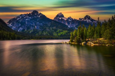 ABD 'nin Wyoming şehrinde Taggart Gölü ve Grand Teton Dağları üzerinde gün batımı. Taggart Gölü Grand Teton Ulusal Parkı 'nda görkemli dağlarla çevrili çarpıcı bir alp gölüdür. Uzun pozlama.
