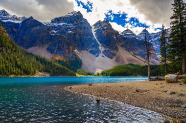 Kanada 'nın Banff Milli Parkı' ndaki Moraine Gölü 'nde Kanada' nın kayalık dağları ve ağır bulutlarla kaplı tepeleri vardır..