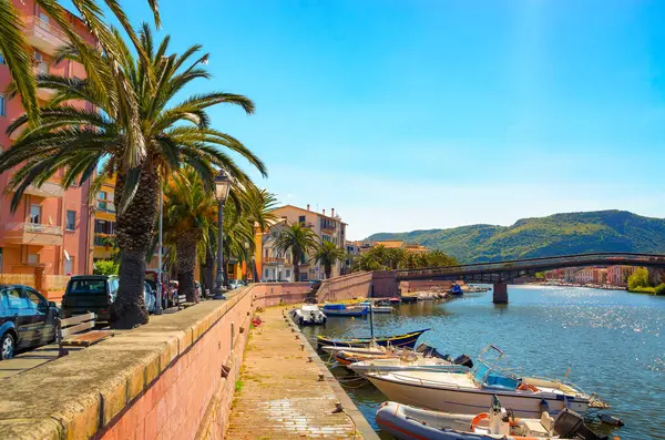 意大利撒丁岛特莫河沿岸的博萨镇风景如画 有小船 五彩斑斓的建筑物和棕榈树 免版税图库照片