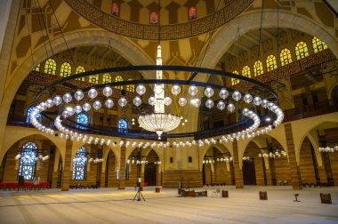 Manama, Bahreyn - 24 Aralık 2023: Büyük bir avize, kemerler, vitray pencereler ve ayrıntılı geometrik desenler içeren El Fetih Büyük Camii 'nin iç mimarisi.